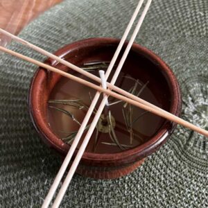 fertige selbstgemachte Citronella Kerze mit Rosmarinzweigen verzieren